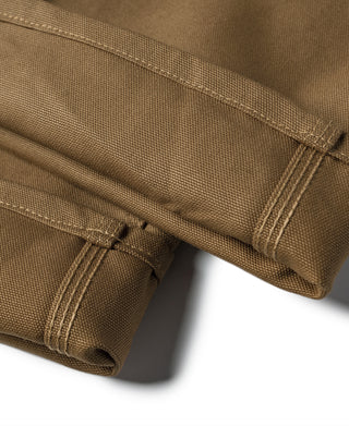 Brown canvas pants cuff close-up with reinforced stitching and folded hem