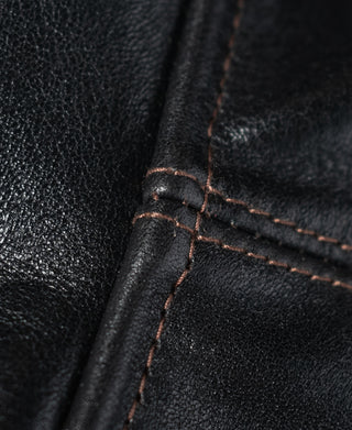 Black leather coat close-up showing reinforced seams and contrast stitching