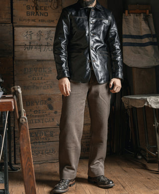 Black leather brakeman coat worn buttoned, with a pointed collar and front pockets