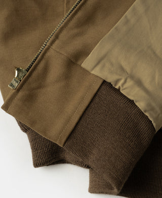 Brown bomber jacket cuff with ribbed knit and zipper pull tag