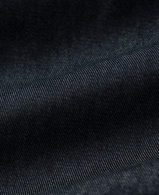 Indigo denim jacket fabric close-up with fine texture and stitched panel edge
