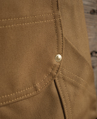 Brown canvas pant seam with small round off-white button