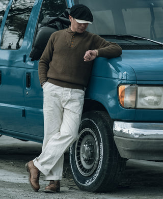 Olive wool high-neck sweater with button placket, worn with light trousers