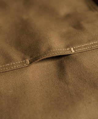 Brown canvas pants seam and curved double-knee patch detail, heavy-duty stitching.
