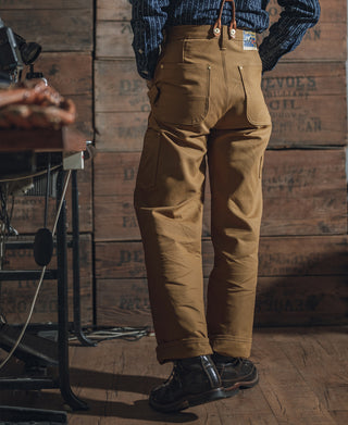 Brown canvas double-knee pants with front and side seams, belt loops, and utility pocket.