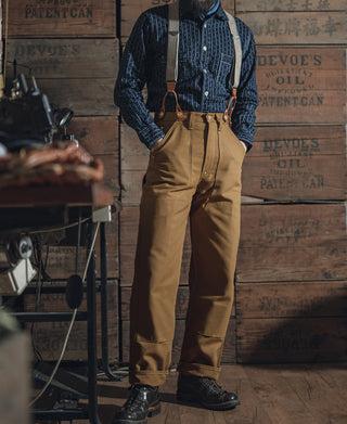 Brown canvas double-knee work pants with cuffed hem, belt loops, and side utility pocket.