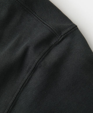 Dark athletic T-shirt side seam and sleeve cuff with ribbed stitching detail.