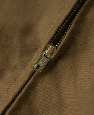 Brown bomber jacket zipper close-up with metal pull and topstitched placket.