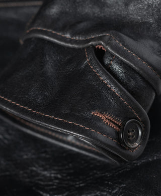 Close-up of a buttoned leather cuff with contrast stitching