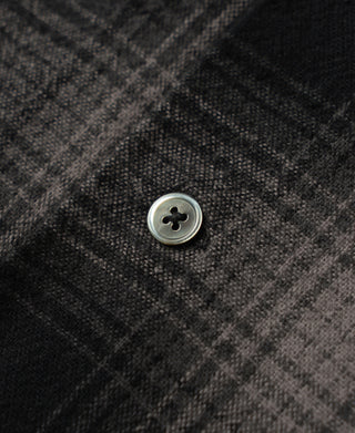 Round metal-look button on black and gray ombre check brushed cotton fabric